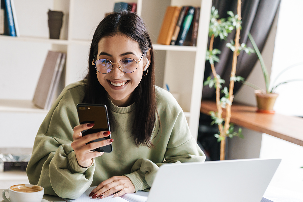 College student sitting in room with coffee, phone, and computer